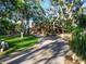 Long, curved driveway leading to an orange home surrounded by mature trees and lush landscaping at 11209 Spring St, Largo, FL 33774