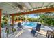 View from the patio with a ceiling fan overlooking the pool and hot tub area and surrounding trees at 11209 Spring St, Largo, FL 33774