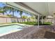 Relaxing backyard view featuring a covered patio, pool, lush lawn, and mature trees at 1140 Mcfarland St, Dunedin, FL 34698