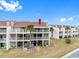 Exterior building view showcasing multi-level balconies with lush grass surrounding the complex at 12360 Capri N Cir # 106, Treasure Island, FL 33706