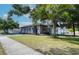 Exterior side view of a gray home with a well-maintained lawn, accented by a mature tree providing ample shade at 12595 95Th N St, Largo, FL 33773