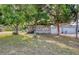 Landscaped front yard with mature trees framing a charming home exterior with a quaint front porch at 12595 95Th N St, Largo, FL 33773