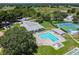 Aerial view of a luxurious community pool, tennis courts, shuffleboard courts and clubhouse at 13003 Titleist Dr, Hudson, FL 34669