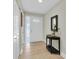 Inviting entryway with light wood floors, a decorative table and mirror, and a white front door with glass window at 1313 Markley Dr, Largo, FL 33770