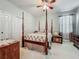 Cozy bedroom featuring a four-poster bed, ceiling fan, and natural light from the window at 13608 Artesa Bell Dr, Riverview, FL 33579