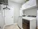 Laundry room with modern appliances, overhead cabinets, and a convenient hanging rack at 13608 Artesa Bell Dr, Riverview, FL 33579