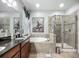 Main bathroom featuring a soaking tub, glass shower, and dual sink vanity with granite countertop at 13608 Artesa Bell Dr, Riverview, FL 33579