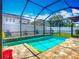A sparkling swimming pool is surrounded by a screened-in enclosure, with brick decking and a vibrant blue sky at 13608 Artesa Bell Dr, Riverview, FL 33579