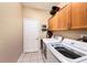 Well-lit laundry room with modern washer and dryer, wood cabinets, and tile flooring at 14042 Marlberry Way, Odessa, FL 33556