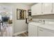 Functional laundry room with white cabinets, modern washer and dryer, and a view of the living room at 1421 Buckner Rd, Valrico, FL 33596