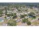 An aerial view shows a yellow single-story home with solar panels surrounded by mature trees in the neighborhood at 1450 Seabreeze St, Clearwater, FL 33756