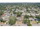 An overhead view of a neighborhood full of mature trees features a yellow single-story home with solar panels at 1450 Seabreeze St, Clearwater, FL 33756