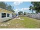 Large, grassy backyard with wood fence, fire pit and brick patio for outdoor seating at 1450 Seabreeze St, Clearwater, FL 33756