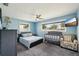 Bright bedroom featuring a bed, crib, chair, and window for natural light and a ceiling fan for temperature control at 1450 Seabreeze St, Clearwater, FL 33756