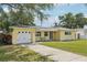 Charming one-story yellow home featuring a well-maintained lawn and a long driveway at 1450 Seabreeze St, Clearwater, FL 33756