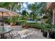 Backyard patio with an umbrella-covered table, surrounded by lush greenery and a glimpse of the pool beyond the fence at 1515 Park N St, St Petersburg, FL 33710