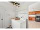 Laundry room featuring appliances and storage shelves; view into the adjacent kitchen at 1613 Comfy Ct, Sun City Center, FL 33573