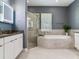 Bathroom featuring a large soaking tub, a glass-enclosed shower, and double vanity sinks at 16220 Lake Armistead Way, Odessa, FL 33556