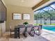 Screened-in patio features travertine tile, a table with seating for eight, pool access, and mounted TV at 16220 Lake Armistead Way, Odessa, FL 33556