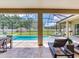 Covered patio offers shade to the pool with travertine tile, lounge chairs and dining space at 16220 Lake Armistead Way, Odessa, FL 33556