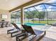 Pool with travertine tile, lounge chairs and outdoor dining space under screened enclosure at 16220 Lake Armistead Way, Odessa, FL 33556