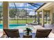Well-maintained travertine tile patio, lounge chairs and pool under a screened enclosure at 16220 Lake Armistead Way, Odessa, FL 33556