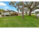 Well-manicured front lawn with mature trees and colorful landscaping leading to a charming single-story home at 1666 Souvenir Dr, Clearwater, FL 33755