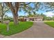 Charming single-story home featuring lush landscaping, a long driveway, and mature trees providing ample shade at 1666 Souvenir Dr, Clearwater, FL 33755