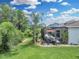 An outdoor living space with a screened-in lanai, a patio set, lush landscaping, and a green lawn at 1696 Hidden Springs Dr, Trinity, FL 34655