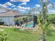 Backyard view of a screened-in pool area with lush landscaping including palm trees, and a well-maintained lawn at 1696 Hidden Springs Dr, Trinity, FL 34655