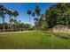 Inviting community entrance with tall palm trees, a manicured lawn, and beautiful landscaping at Fox Wood at 1712 Crossvine Ct, Trinity, FL 34655