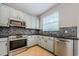 Light-filled kitchen showcasing stainless steel appliances, gray cabinets, and stylish backsplash at 1712 Crossvine Ct, Trinity, FL 34655