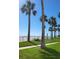 Beautiful beach view with palm trees, lush grass, and beach chairs at 17960 Gulf Blvd # 101, Redington Shores, FL 33708