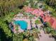Aerial view of a community clubhouse and pool featuring palm trees, red umbrellas, and ample seating for relaxing by the pool at 19836 Hidden Glen Dr, Land O Lakes, FL 34638