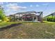 View of a screened-in pool area with outdoor seating in a grassy backyard at 19836 Hidden Glen Dr, Land O Lakes, FL 34638