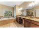 Bathroom featuring dual sinks, granite counters, tile floors, a soaking tub and a glass shower at 2637 Yukon Cliff Dr, Ruskin, FL 33570