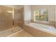 Bathroom featuring glass enclosed shower and soaking tub, tile floors and natural lighting at 2637 Yukon Cliff Dr, Ruskin, FL 33570