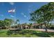 View of clubhouse with American flag, well-manicured lawn, and circular driveway at 3174 Eagles Landing W Cir # 58, Clearwater, FL 33761