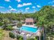 Aerial view of community pool with a whirlpool, lounge chairs, lush landscaping, and clubhouse at 3505 Tarpon Woods Blvd # N405, Palm Harbor, FL 34685