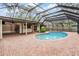 Inviting screened-in pool area featuring brick pavers and an adjacent outdoor bar area at 3604 Arlington Oaks Ct, Tampa, FL 33618