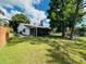 Backyard view showing the home's screened-in patio, lush lawn, and mature trees providing shade at 3845 Edgemont Dr, New Port Richey, FL 34652