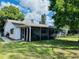 Exterior view of the home featuring a screened-in patio, well-manicured lawn, and mature trees at 3845 Edgemont Dr, New Port Richey, FL 34652