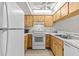 Compact kitchen featuring white appliances, light wood cabinets, and modern laminate flooring at 39650 Us Highway 19 N # 553, Tarpon Springs, FL 34689
