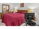 Comfortable main bedroom with wooden dresser, mirror, lamps, and red quilt at 39650 Us Highway 19 N # 553, Tarpon Springs, FL 34689