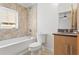 Bright bathroom featuring a tub with a window, a toilet, and a vanity with granite countertop at 512 S Glen Ave, Tampa, FL 33609