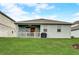 Backyard with a lawn, patio, grill and a view of adjacent homes at 5413 Wishing Arch Dr, Apollo Beach, FL 33572