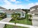 Aerial view of a light blue home with a two-car garage, a paver driveway, and a well-maintained lawn at 5413 Wishing Arch Dr, Apollo Beach, FL 33572
