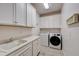 Well-lit laundry room featuring white cabinetry, countertops, sink, washer, and dryer at 5413 Wishing Arch Dr, Apollo Beach, FL 33572