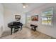 Sunlit piano room with a black grand piano, sewing machine and two windows overlooking lush greenery at 5413 Wishing Arch Dr, Apollo Beach, FL 33572