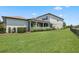 Expansive backyard with lush green lawn, mature landscaping, and a screened-in patio at 5717 Village Center Dr, Lithia, FL 33547